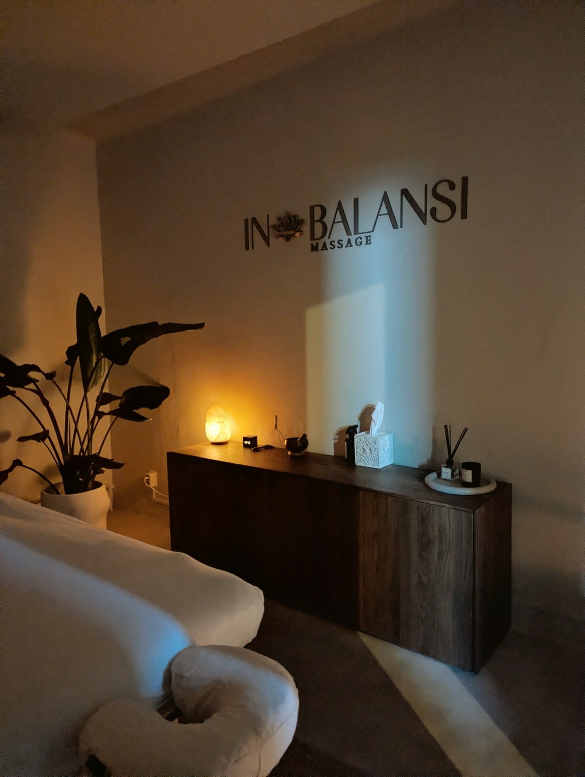 Behandelruimte van IN BALANSI met massagetafel, plant en zoutlamp